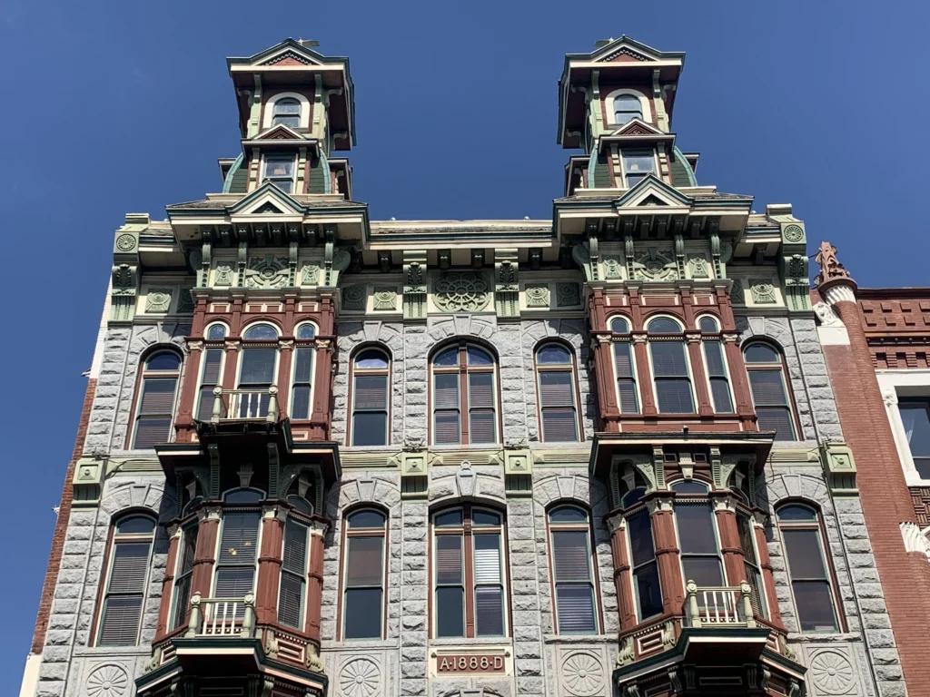 Ornate 1888 Victorian building facade with two turrets and decorative bay windows.