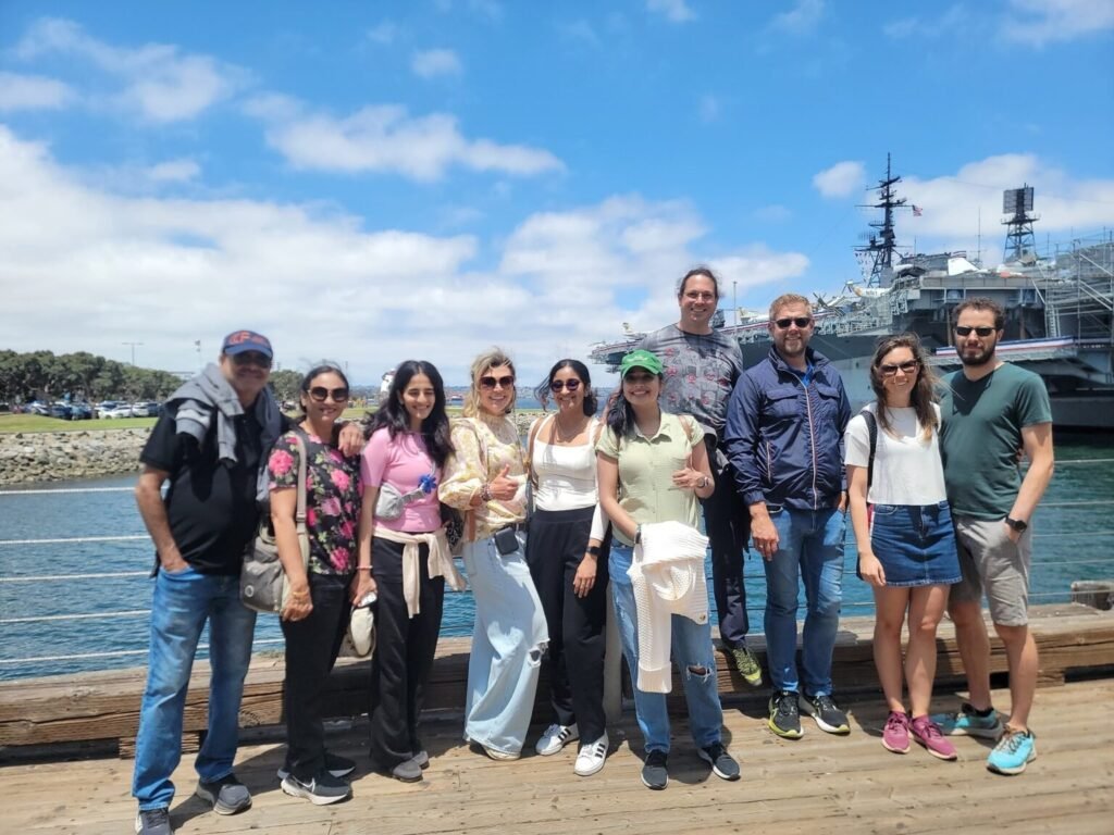 Group of tourists and tour guide near USS Midway landmark in San Diego.
